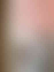 wallpaper by Imogen Heath Interiors. Bathroom with wavy pink and red wallpaper, striped tiles, curved mirror, ribbed white sink, brass faucet, and hanging towels. Modern style.