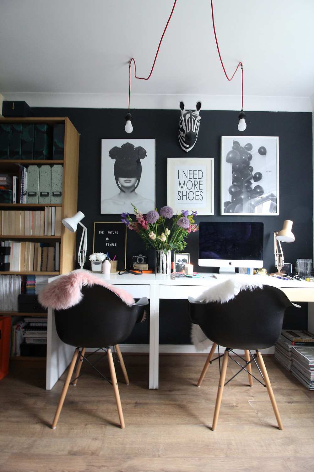 A FASHION vlogger INSPIRED HOME OFFICE with white IKEA desks and EAMES black chairs in front of a black wall with fashion posters.