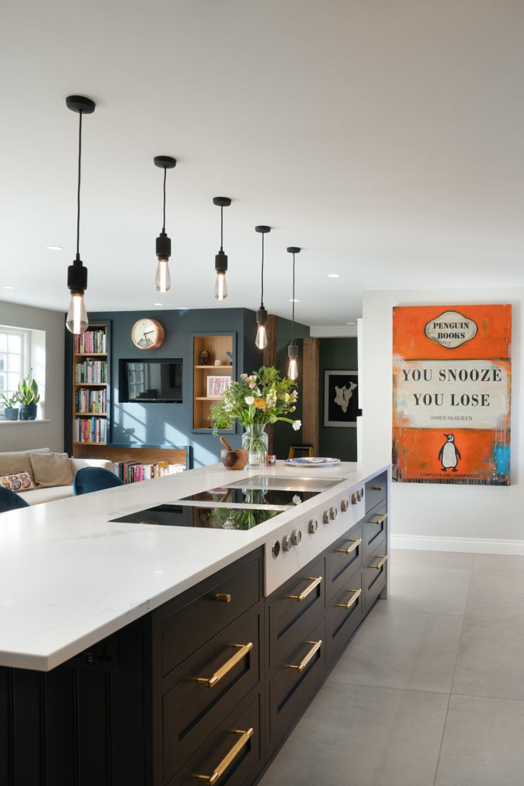 Modern kitchen with white countertops, black cabinets, hanging lights, and a vibrant orange poster reading "You Snooze You Lose."