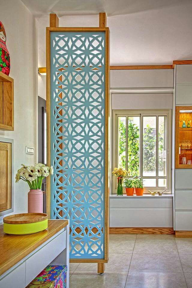 Sunny room with blue lattice divider, daisies in pink vase, and colorful pots on windowsill. Bright, cheerful decor.