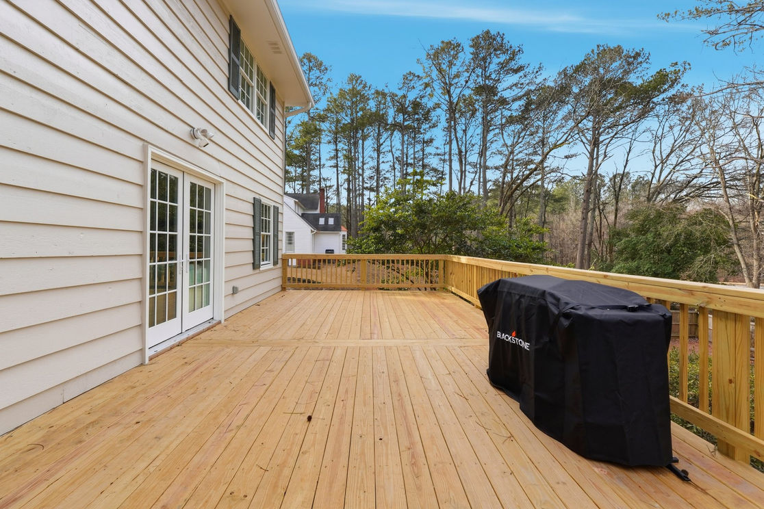 Large wooden deck spanning the length of the house, gas grill and wooden railings