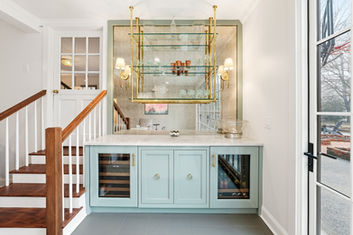 Mirrored bar cabinet with seafoam green cabinets, gold shelves and gold fixtures