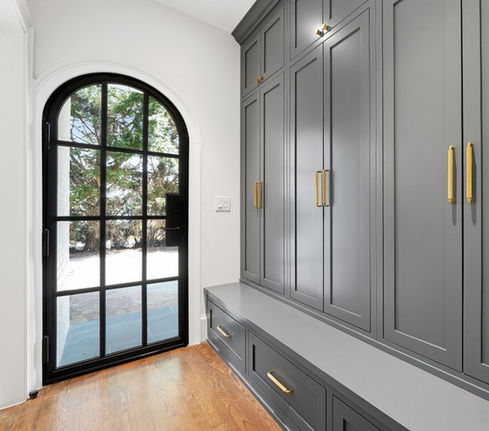Mud room with grey blue storage cabinets and glass door with black frame