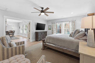 Basement bedroom with queen size bed, striped chair, double windows with lots of light