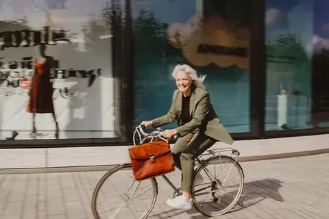 Unternehmerin fährt lächelnd Fahrrad durch die Stadt – lebendige Personal-Branding-Aufnahme mit moderner, dynamischer Wirkung.