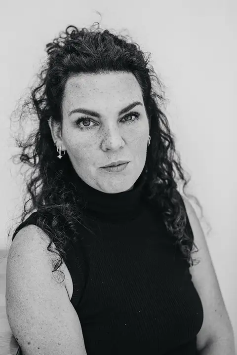 Schwarz-weiß Porträt einer Frau mit lockigen Haaren und intensivem Blick – emotionale und ausdrucksstarke Businessfotografie.