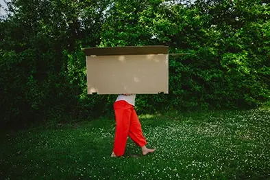 Person trägt einen großen leeren Rahmen durch eine Wiese – kreative Personal-Branding-Aufnahme mit viel Raum für Interpretation und Persönlichkeit.