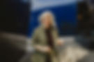Selbstbewusste Businessfrau mit silberblonden Haaren in olivgrünem Hosenanzug, lachend in moderner urbaner Umgebung. Authentisches Personal-Branding-Foto mit natürlicher Ausstrahlung, das Professionalität, Nahbarkeit und Selbstvertrauen vermittelt.