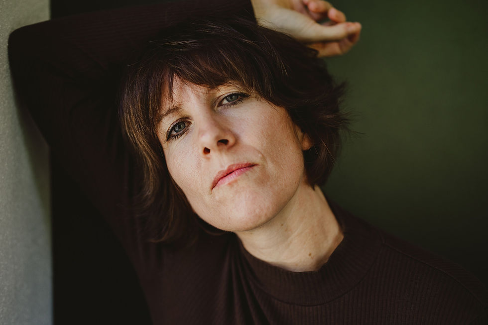 Eine Frau lehnt an einer Wand, hat den  Kopf angelehnt und schaut zufrieden aus.