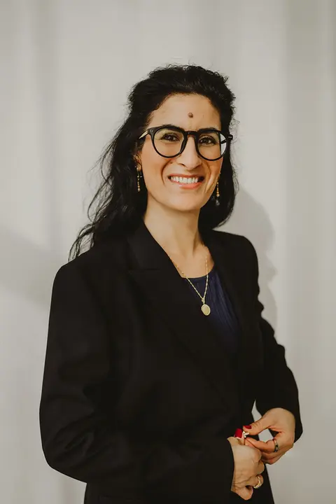 Selbstbewusste Unternehmerin mit Brille und dunklem Outfit vor neutralem Hintergrund – modernes Personal-Branding-Porträt mit professioneller Ausstrahlung.