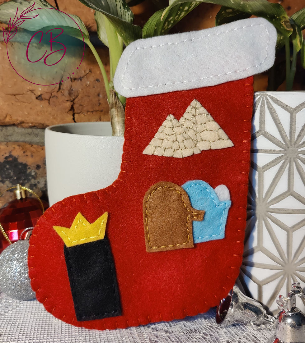Red felt stocking with desert scenes hangs against a brick wall, beside a potted plant. A Christmas ornament is visible nearby.