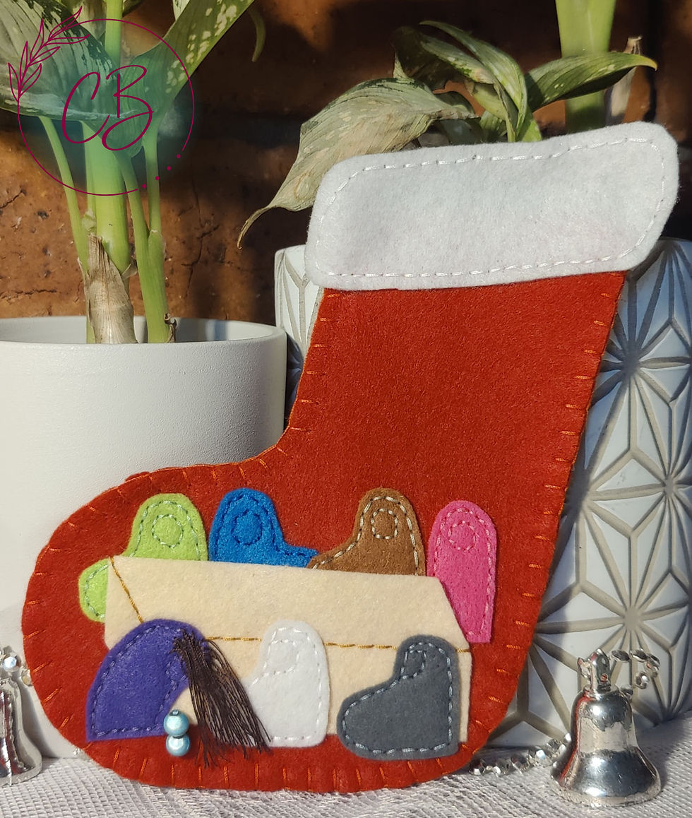 Red felt Christmas stocking with colorful felt decorations on a table, plants in background. Silver bells and white pots add festive touch.