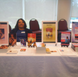 Sherlyn Powell smiling behind a display table with books