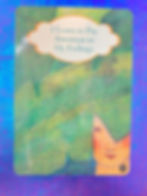 A picture of an oracle card with an image of a lady peeking through underneath  a banana tree leaf.