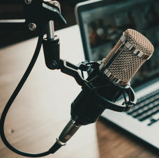 A microphone set up for podcasting or a radio host with an open laptop set up in the background.