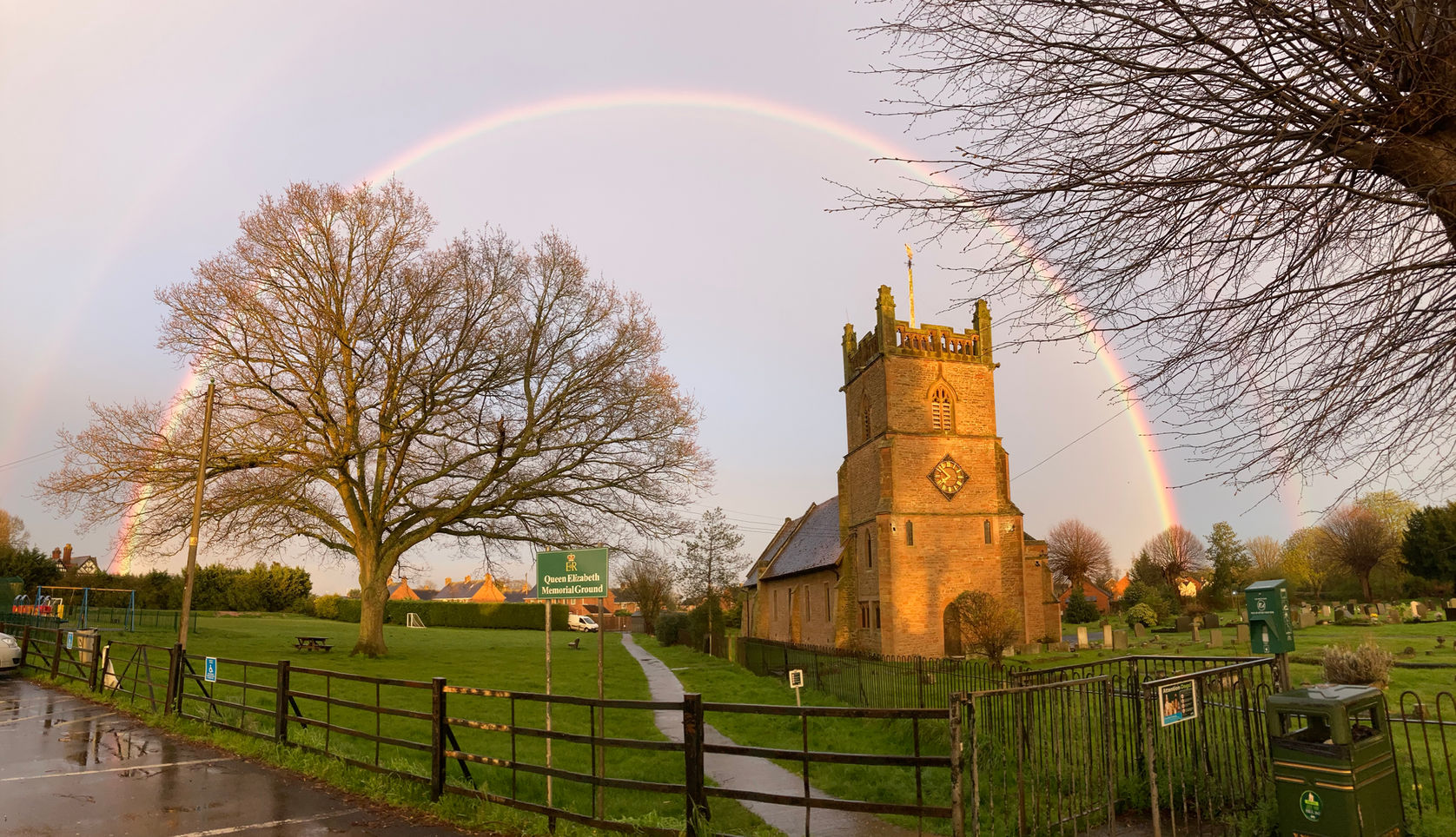 Christ Church in Lower Broadheath, Worcestershire, with a rainbow arching over the historic church building, churchyard, and Queen Elizabeth Memorial Ground.
