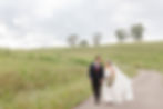 A just married couple walking through the field at the Manor at Breckenridge wedding venue