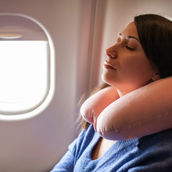 a woman with a travel pillow sitting on an airplane