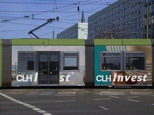 CLH Invest advertisement on a green urban tram in a city.