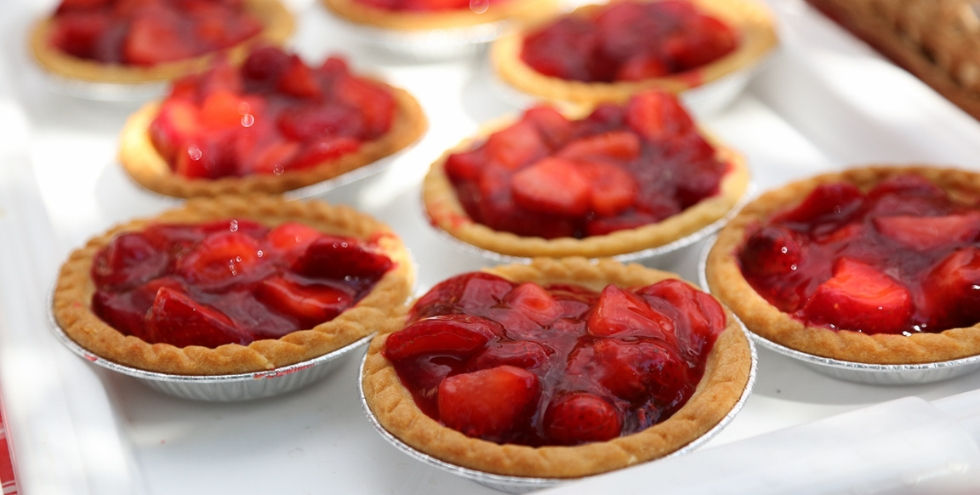 Strawberry Festival in Niagara-on-the-Lake. Mini strawberry tarts with glossy red filling on a white tray, close-up of several bite-sized pies in foil cups.