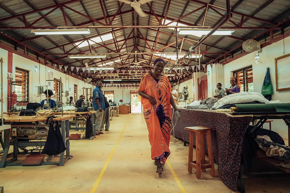 A women in an orange dress walks through a clothing factory