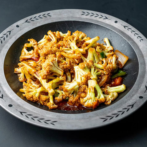 Cauliflower dish in a bowl, spicy and delicious, served on a table.