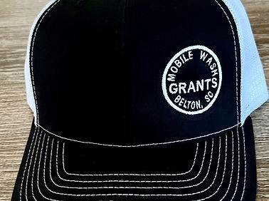 This is a close-up image of a black and white trucker cap featuring a white mesh back and prominent white stitching on the br
