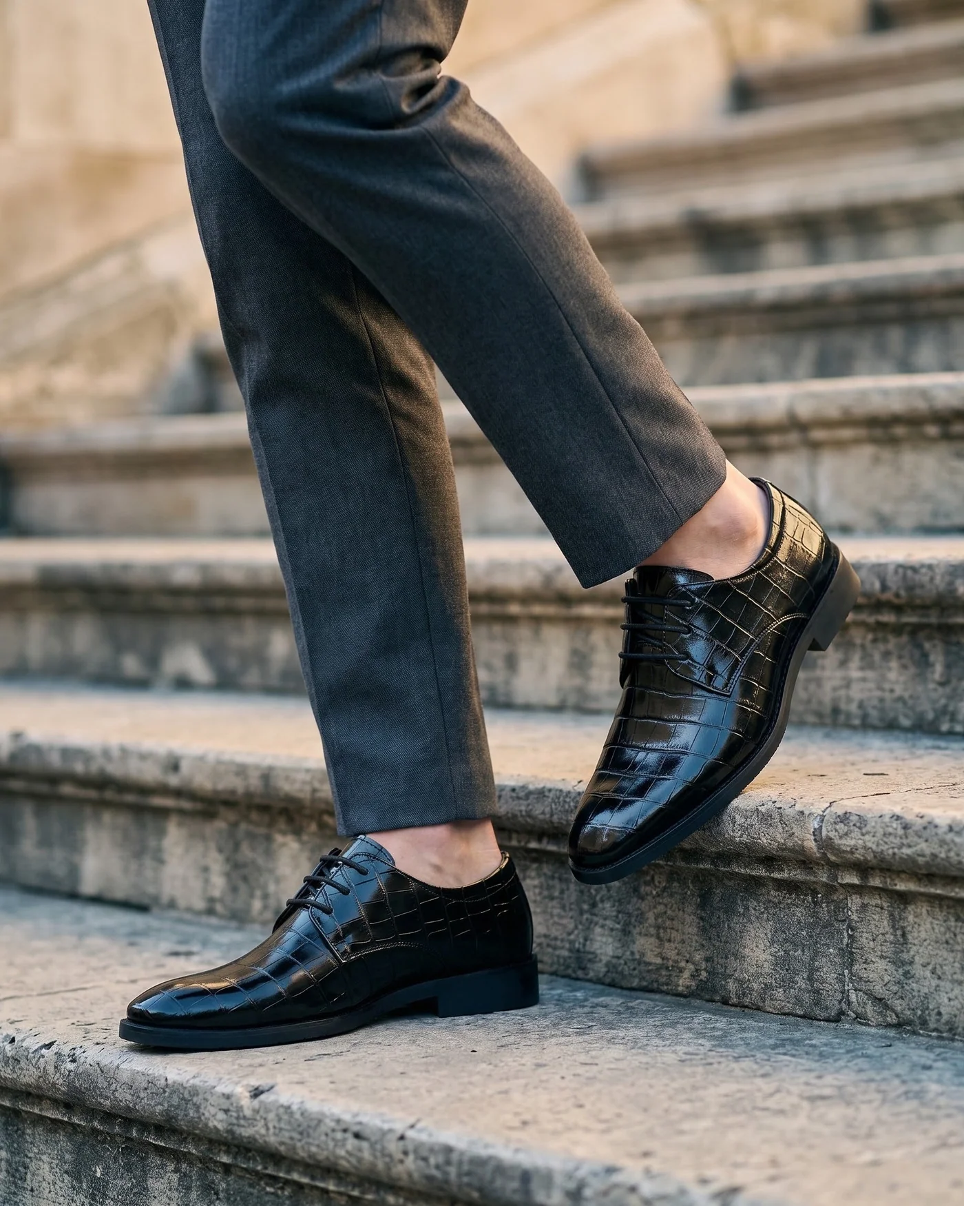 Polished black textured leather lace-up shoes with tailored trousers on stone steps