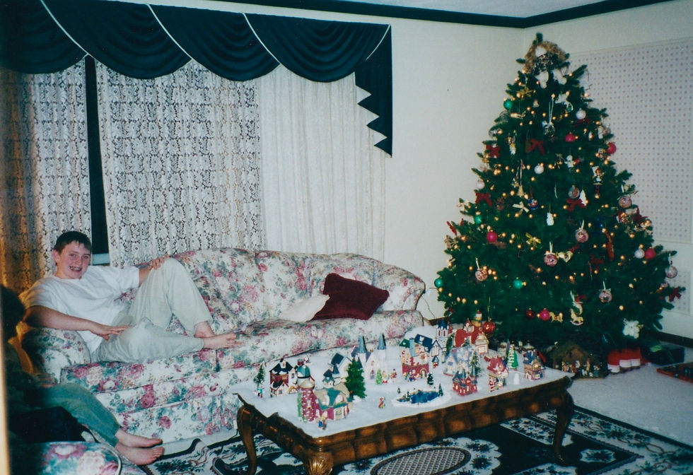 Me, posing behind a coffee table playing host to a Christmas village, December 2000