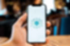 Hand holding smartphone displaying AI graphic. Background is softly blurred, with warm tones and bokeh effect, creating a tech-focused mood.