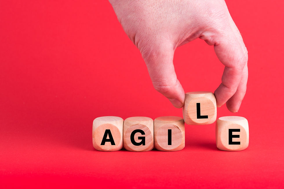 Hand arranges wooden blocks spelling AGILE on red background, emphasizing adaptability and motion.