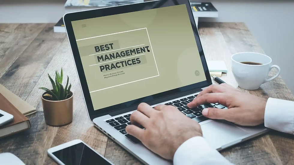 Hands typing on a laptop showing "Best Management Practices." A cup of coffee, smartphone, plant, and notebook are on the wooden table.