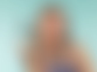 Mulher sorrindo segura produtos de cabelo em fundo azul claro. Ela veste blusa cinza. Embalagens verdes com texto visÃvel. Emocional alegre.