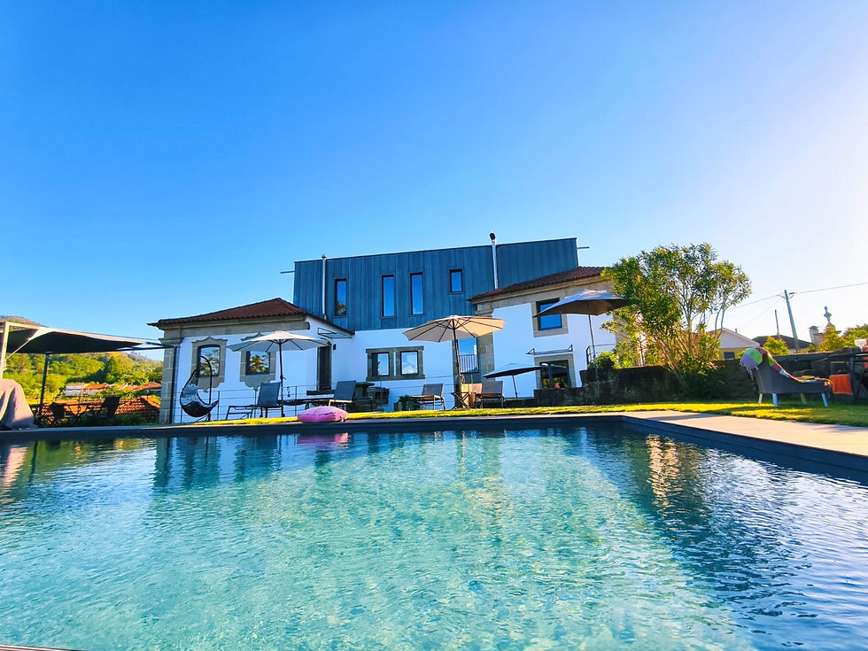 Casa moderna com piscina azul em um dia ensolarado. Guarda-sóis e plantas no entorno, criando um clima relaxante e tranquilo.