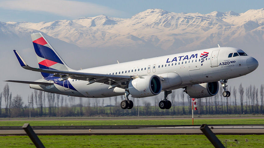 Avião da LATAM A320 Neo aterrissa em pista, montanhas nevadas ao fundo. Cores brancas e azuis predominam, céu limpo.