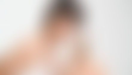 Mulher de cabelo curto sorri enquanto segura um frasco transparente de creme "fresh" em fundo branco. Veste roupa branca, transmitindo leveza.