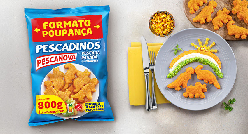 Pacote azul de Pescadinos em formato de dinossauro ao lado de um prato decorativo com comida em forma de arco-íris. Fundo cinza claro.