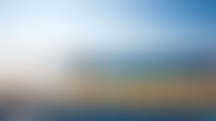 Mulher correndo no deck de um navio sob céu azul. Cadeiras de praia estão dispostas ao lado. O mar e montanhas ao fundo. Atmosfera ensolarada.