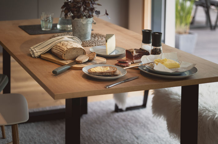 Gedeckter Holztisch mit Geschirr und Gläsern im Essbereich des Lieblingsplatzes.
