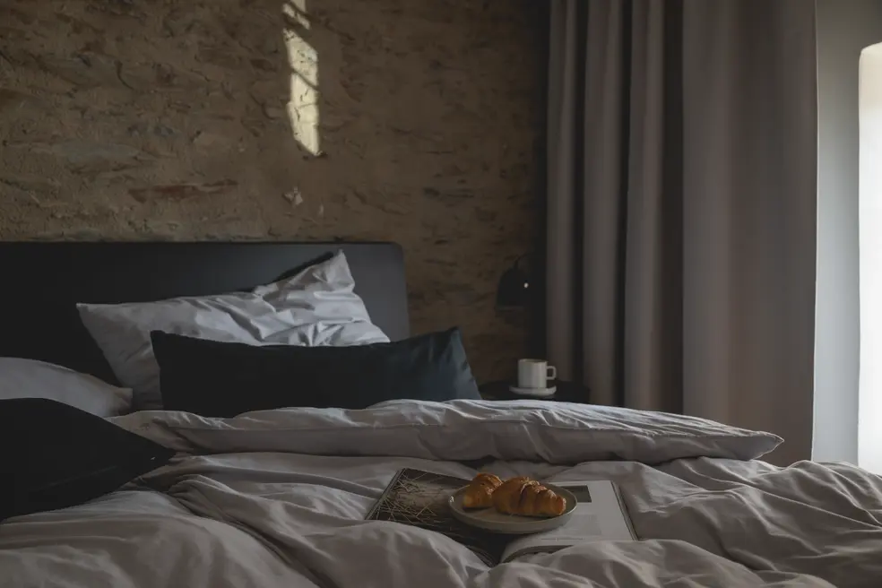 Schlafzimmer mit Natursteinwand und ruhiger Lichtstimmung