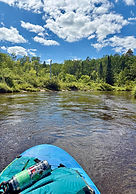 An empty stand-up paddleboard on a winding stream with tight U-curves, capturing the serene exploration offered on SUP trips
