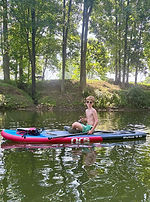 Angler spin fishing from a stand-up paddleboard on calm river water, combining balance and skill on a Shenandoah Valley Adven