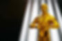 Hollywood Golden Oscar Academy award statue on light rays on black background with copy sp