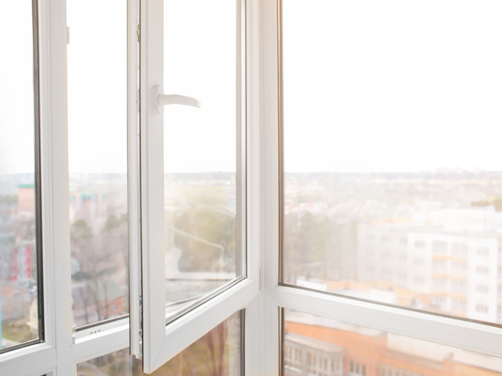 Offenes weißes Fenster mit hellem Blick auf eine städtische Skyline.