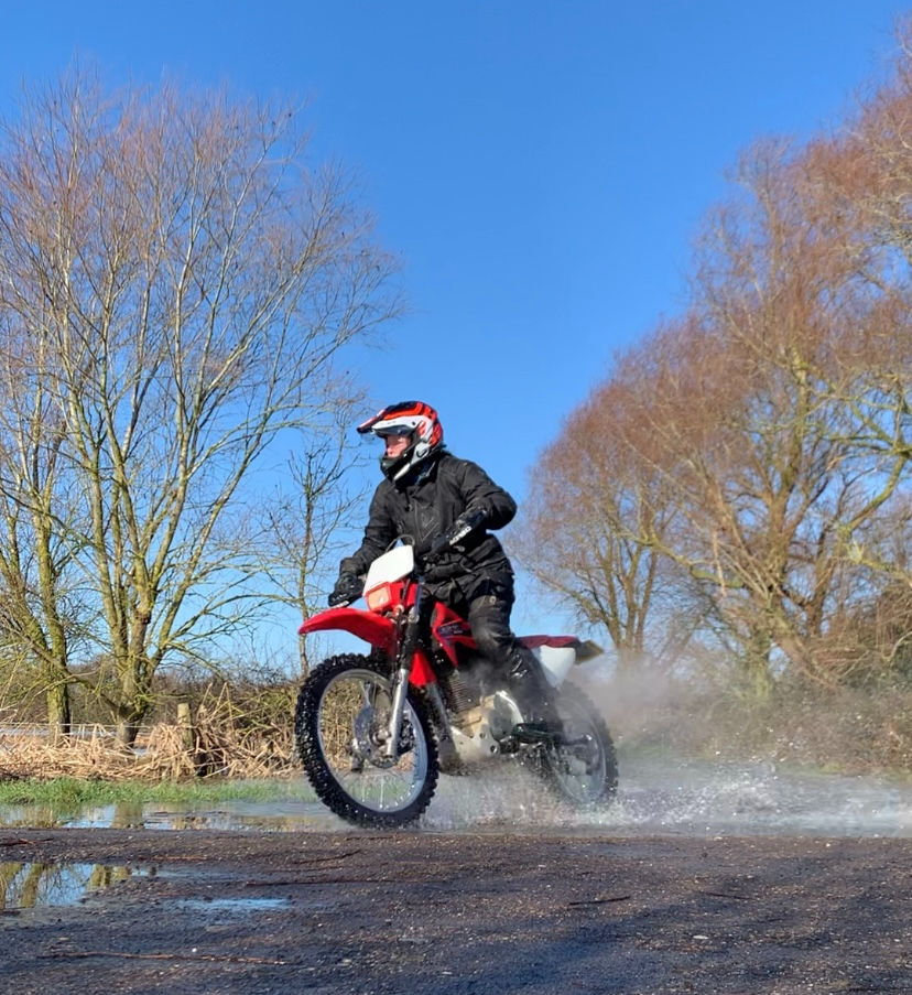 A trail bike splashing through a puddle