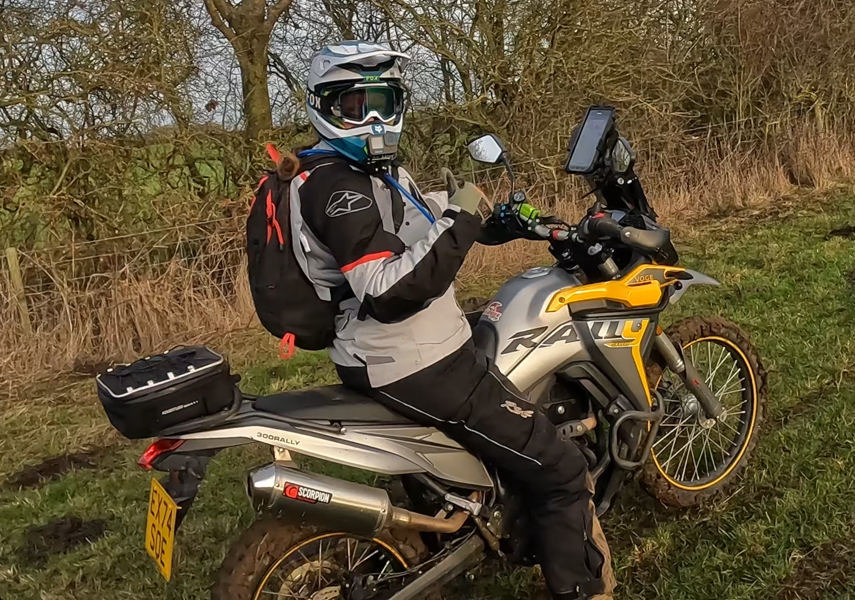 An adventure bike rider wearing winter gear gives a thumbs up.