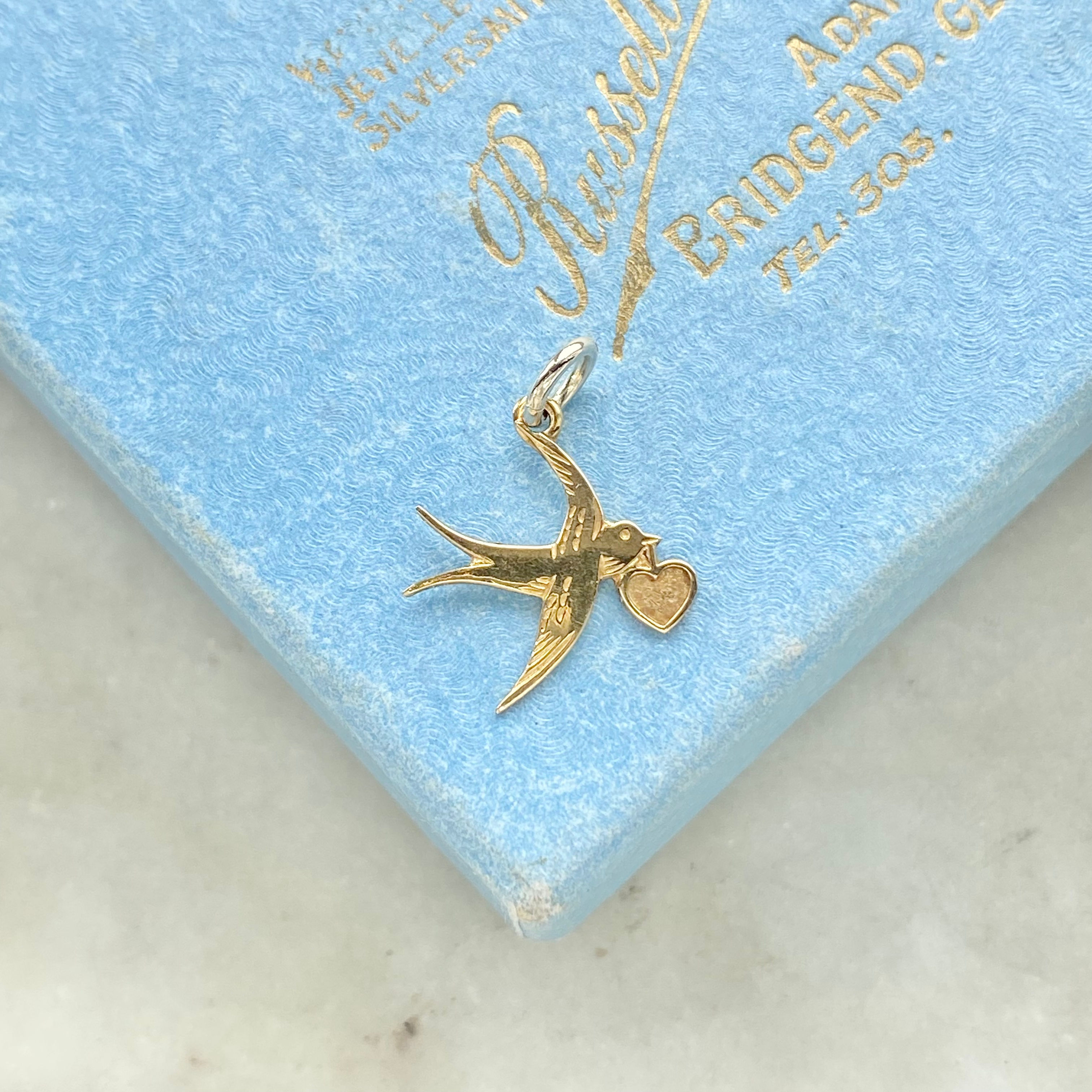 Vintage 1984 9ct gold swallow carrying a heart charm