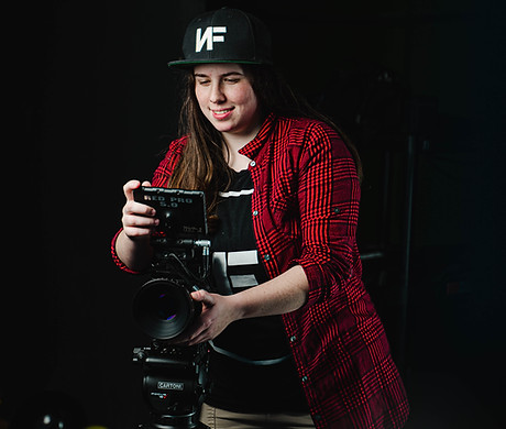 A woman behind a camera, smiling