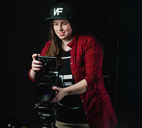 A woman behind a camera, smiling