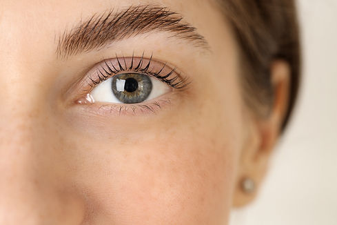 Beautiful woman after lash laminating and tinting procedure on light background, closeup.j